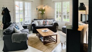 A modern living room with a fireplace, large windows, and a cozy seating area. - COSY house 600 m from the beach, ideal for families - (Agon-Coutainville)