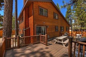 A log cabin with a deck, outdoor seating, and a fenced yard.