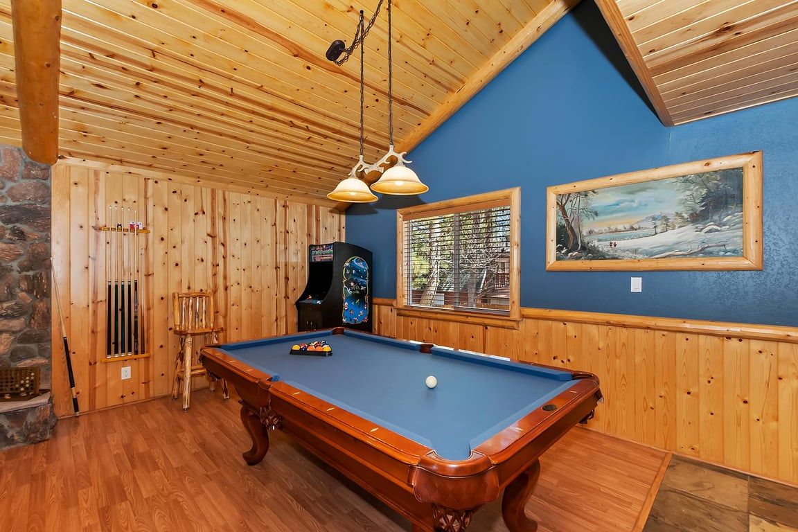 A pool table in a room with wooden walls and a sloped ceiling.