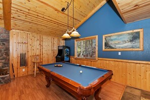 Une table de billard dans une pièce aux murs en bois et au plafond en pente.