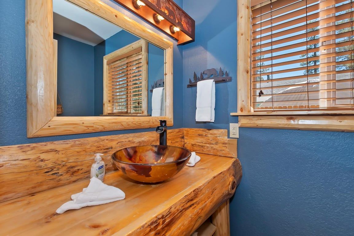 Un bagno con un mobile lavabo in legno, uno specchio grande e una finestra con persiane.
