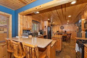 A kitchen with wooden cabinets, granite countertops, and a central island with bar stools.