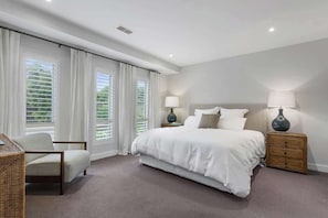 A bedroom with a large bed, a chair, a nightstand, and a lamp.