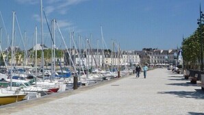Ein Yachthafen mit zahlreichen Booten, die an einer gepflasterten Uferpromenade liegen.