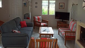 Ein Wohnzimmer mit grauem Sofa, einem Holztisch, einem gestreiften Sofa und einem Fernseher.