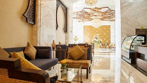 Een moderne lobby met een bank, stoelen, een salontafel en een decoratieve wand.