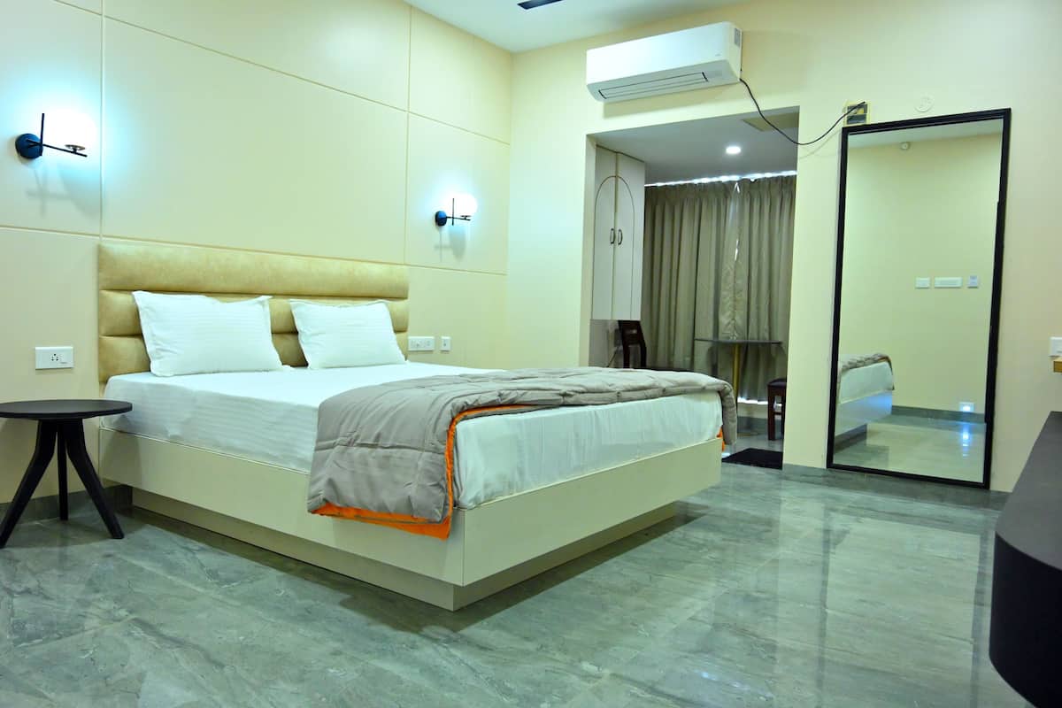 Une chambre d’hôtel équipée d’un lit, d’une petite table, d’un miroir et d’un appareil de climatisation.