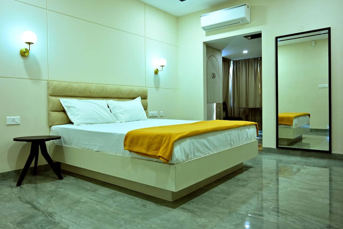 Une chambre d’hôtel équipée d’un lit, d’une table de chevet, d’une lampe fixée au mur, d’un appareil de climatisation et d’un miroir.