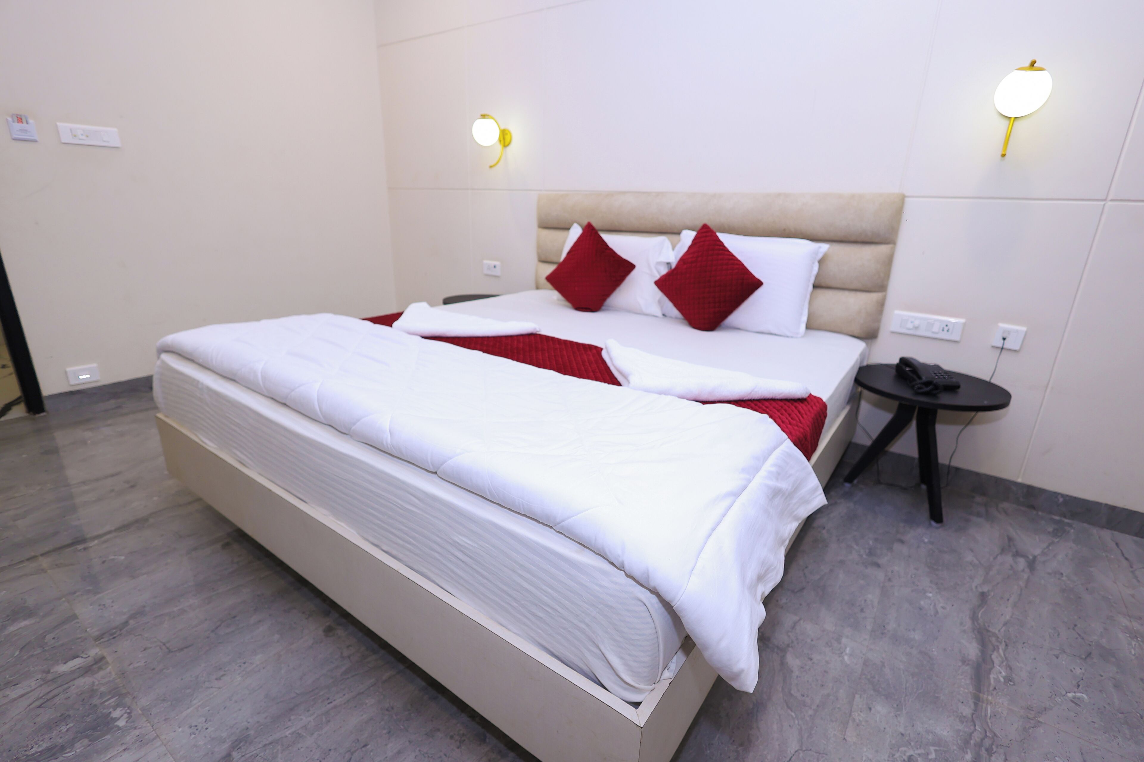 A hotel room with a large bed, two bedside tables, and wall-mounted lights.
