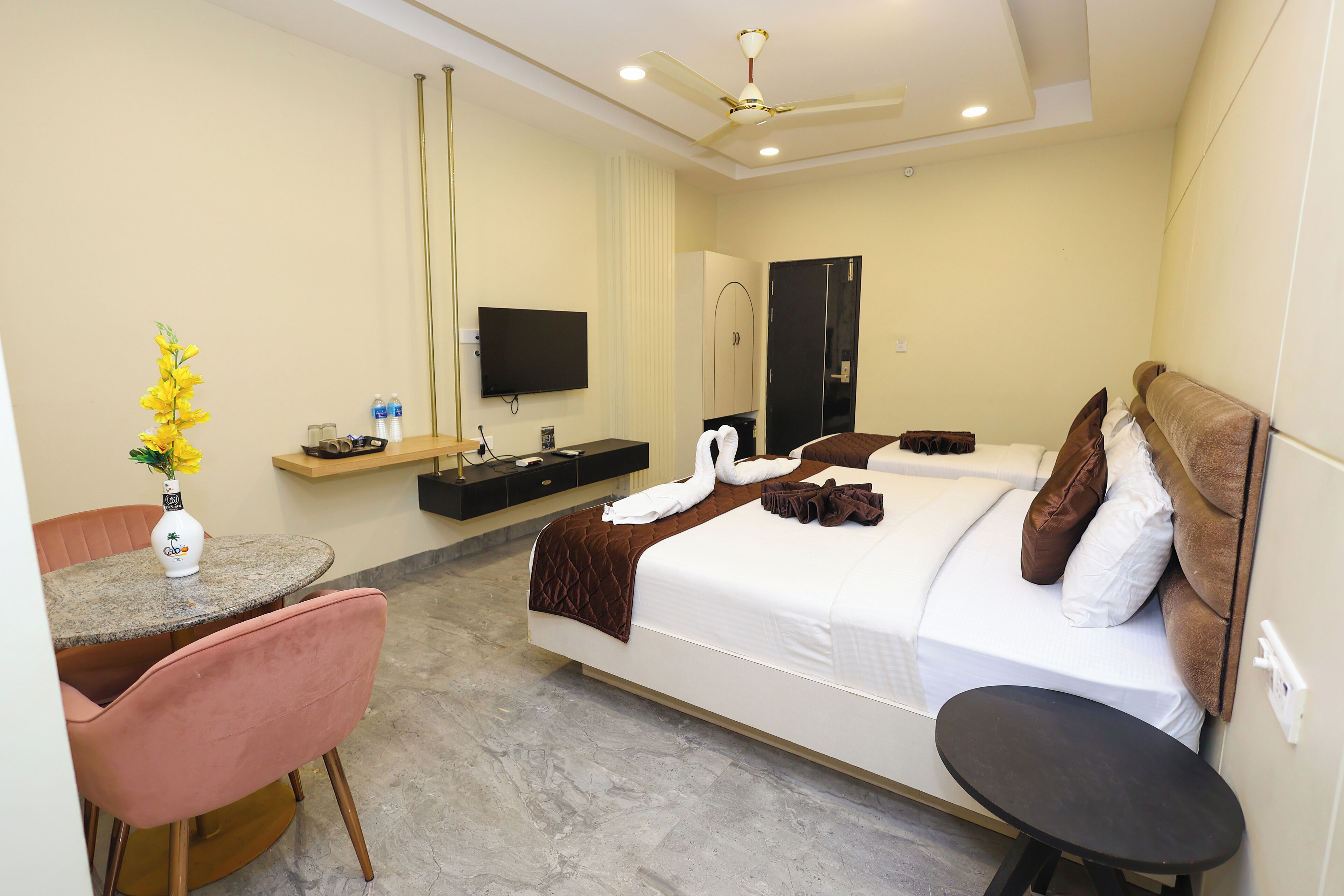 Une chambre d’hôtel équipée d’un lit, d’un bureau, d’une chaise, d’une télévision et d’un ventilateur de plafond.