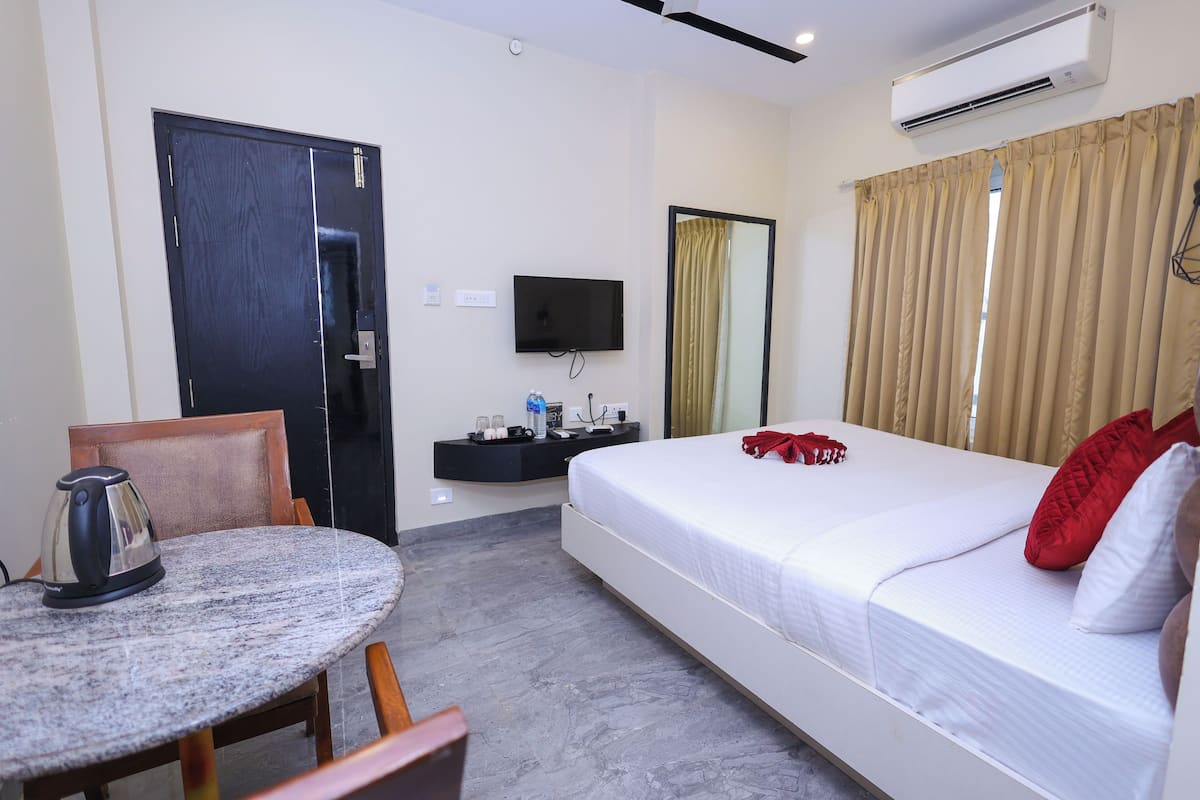 Une chambre d’hôtel équipée d’un lit, d’une télévision, d’un bureau avec une bouilloire et d’une chaise.