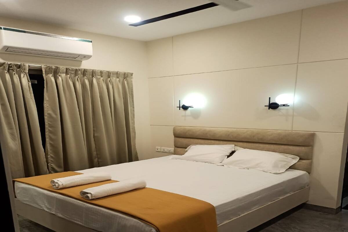 Une chambre d’hôtel équipée d’un lit, de rideaux, d’un climatiseur et de lampes fixées au mur.