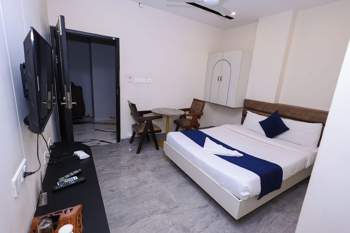 Une chambre d’hôtel comprenant un lit, un bureau avec une télévision, une chaise et une armoire.