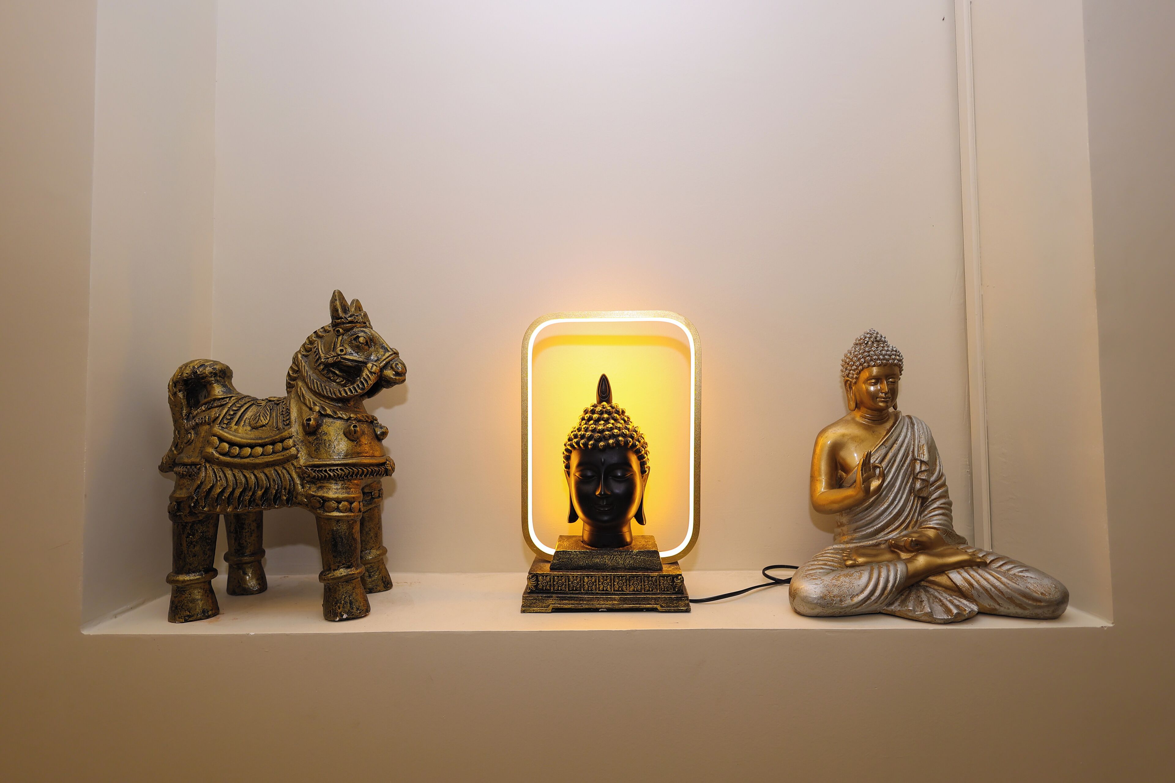 A shelf with three statues: a horse, a Buddha, and a seated Buddha.