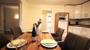 A dining area with a wooden table set for four, including plates, glasses, and a bottle of wine.