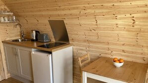 Una cocina compacta con un lavamanos, cafetera, lavavajillas y una mesa con un cuenco de naranjas.