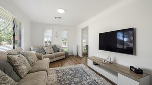 A modern living room with a sectional sofa, a flat-screen TV, and a wooden console table.