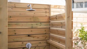 Une cabine de douche en bois, dotée d’un pommeau de douche intégré et d’un porte-serviettes.