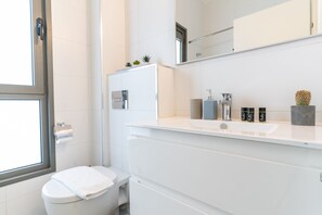 Een moderne badkamer met toilet, wastafel en spiegel.