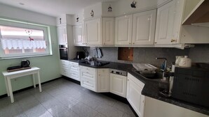 Una cocina con armarios blancos, encimera negra y ventana con vistas a un edificio.