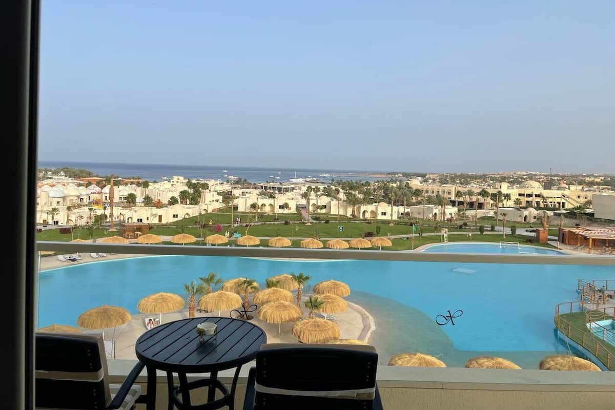 A poolside view with a clear view of the ocean and resort buildings in the background.