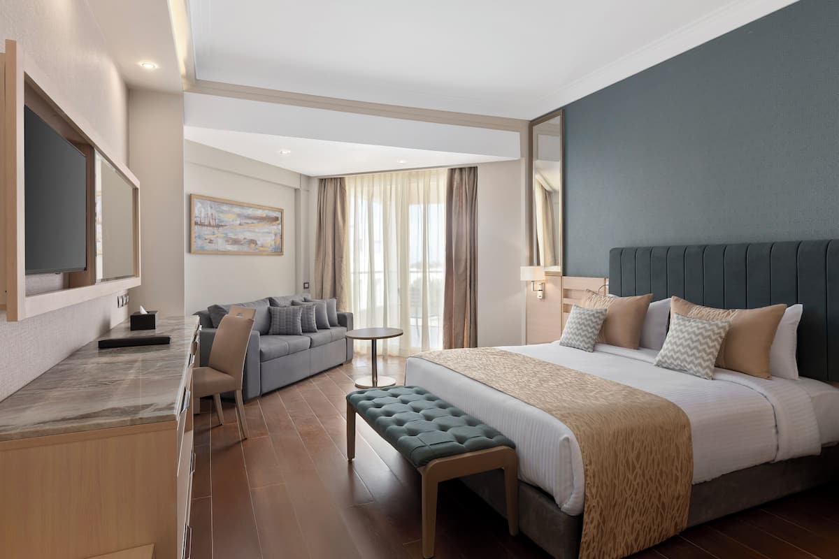 A hotel room with a bed, a desk, a chair, a sofa, and a small table.