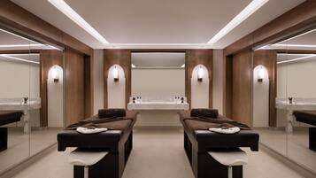 Un moderno spa con dos camillas de masaje, un lavabo central e iluminación empotrada.