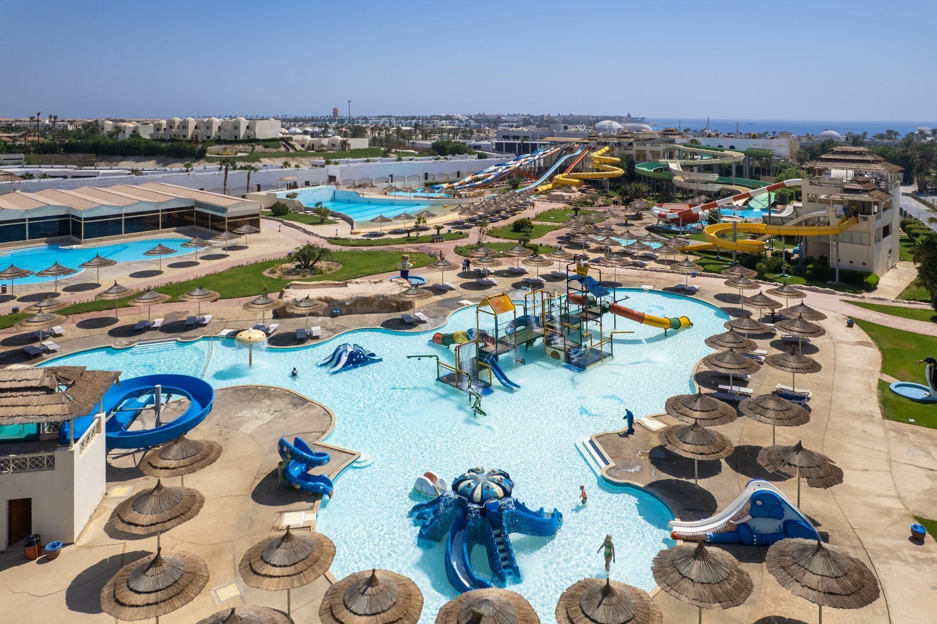 A large water park with multiple pools, slides, and a large blue water slide.