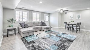 A modern living room with a sectional sofa, a dining table with chairs, and a ceiling fan. - 2 Mi to Dtwn Gilbert! Snowbird Escape w/ Pool (Gilbert)