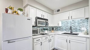A modern kitchen with white cabinets, a stainless steel refrigerator, a microwave, and a tiled backsplash. - 2 Mi to Dtwn Gilbert! Snowbird Escape w/ Pool (Gilbert)