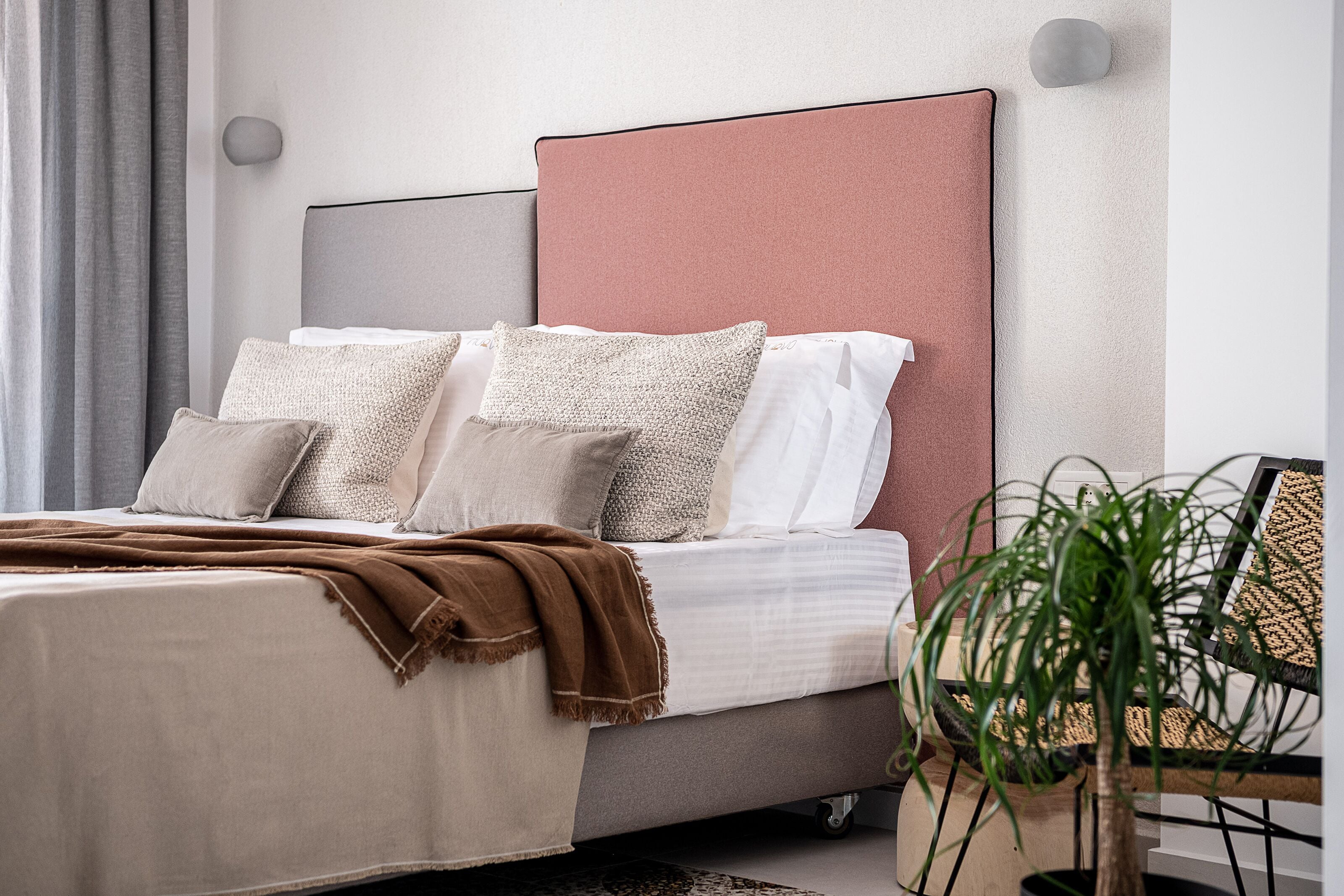 A neatly made bed with a brown blanket, a grey headboard, and multiple pillows.