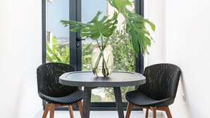Un balcon avec deux fauteuils en osier, une table ronde et une grande plante.