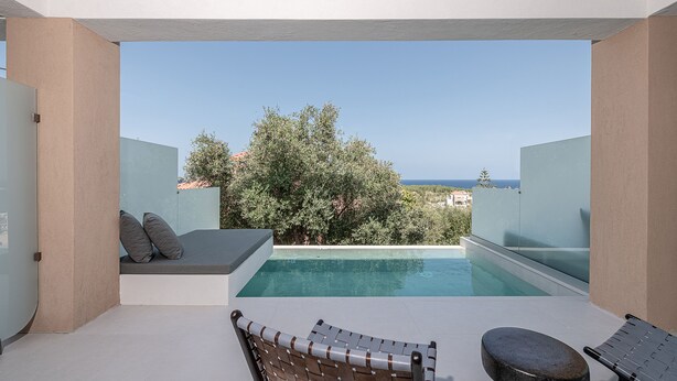 Un espace piscine extérieur moderne offrant une vue dégagée sur la mer, un coin salon avec des coussins et une chaise longue.