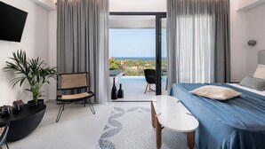 Une chambre d’hôtel moderne équipée d’un lit, d’une table à manger, d’une télévision et offrant une vue sur l’océan.