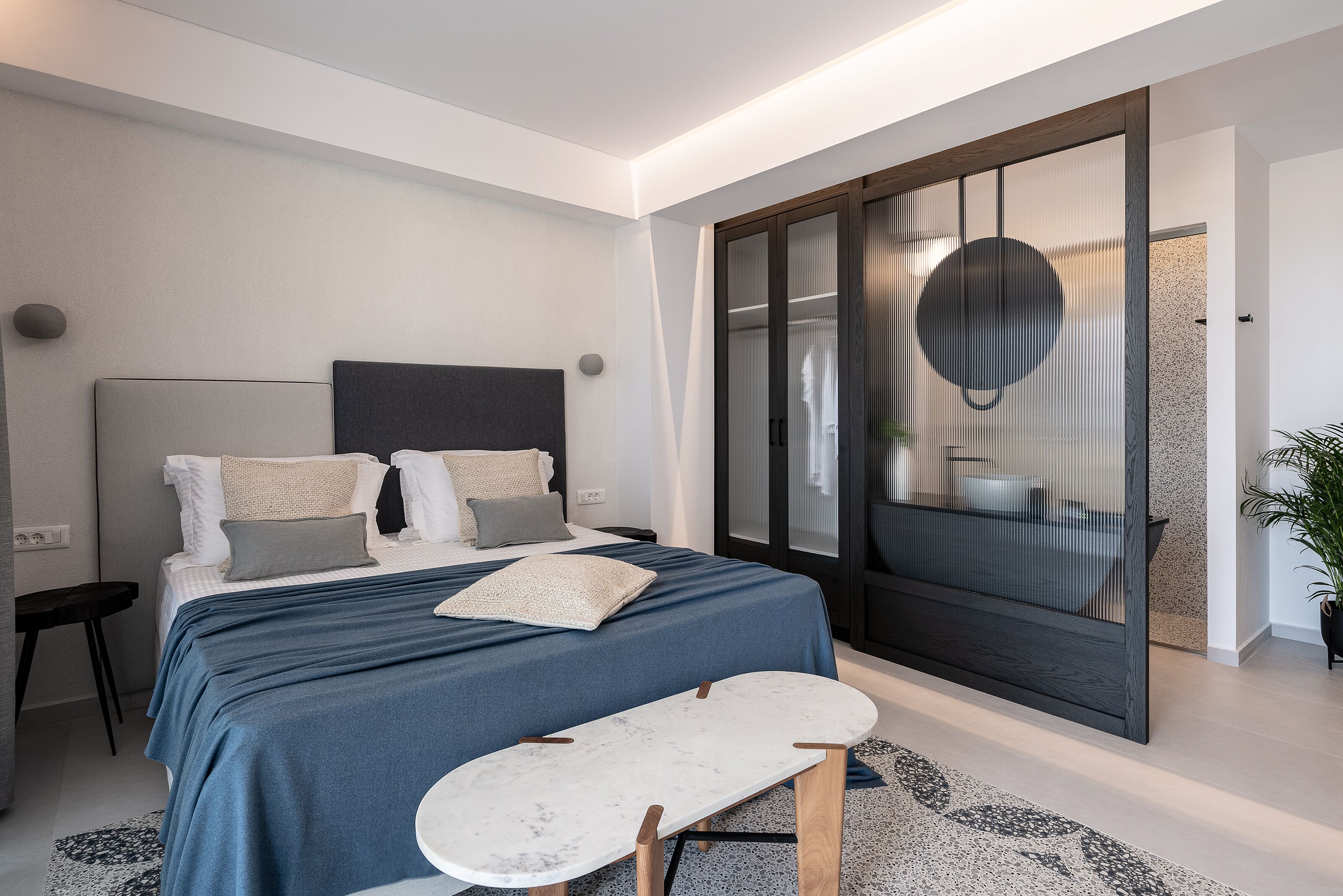 A modern bedroom with a bed, bedside tables, and a large window with a view.