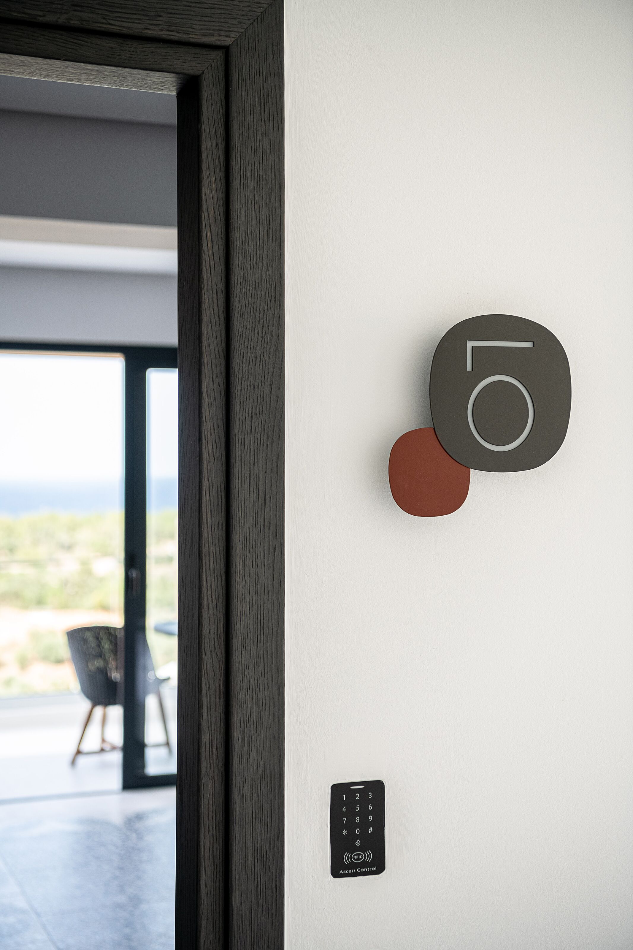 Un intérieur moderne au design minimaliste, doté d’un clavier numérique et offrant une vue à travers une porte en verre.