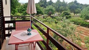 Varanda com mesa, cadeira e guarda-sol.