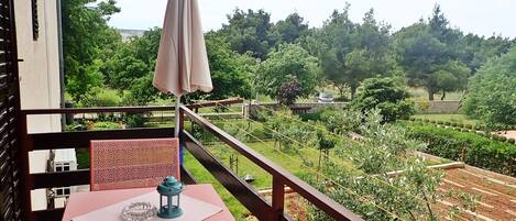 A balcony with a table, chair, and umbrella.