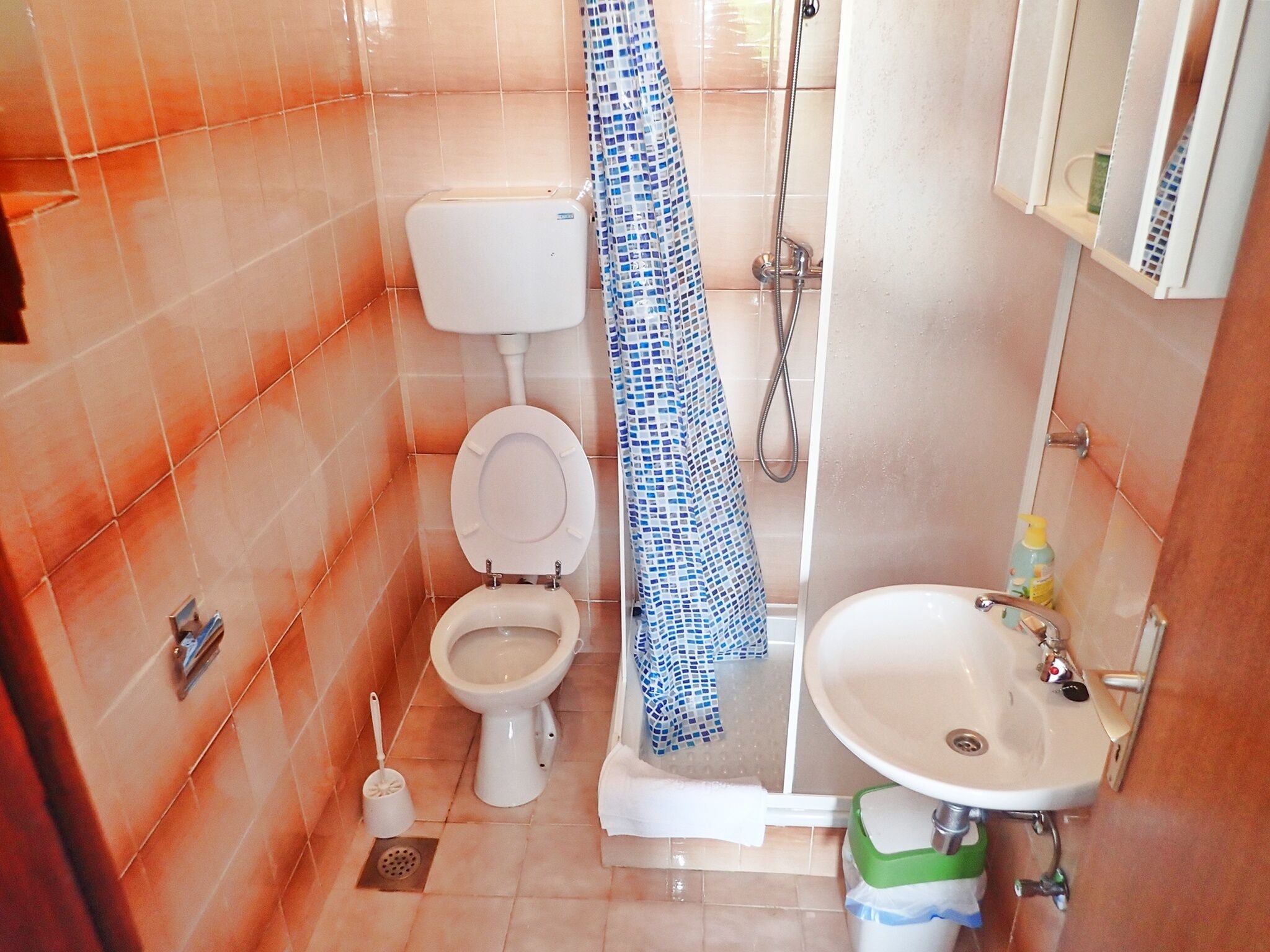 A bathroom with a toilet, shower, and sink.