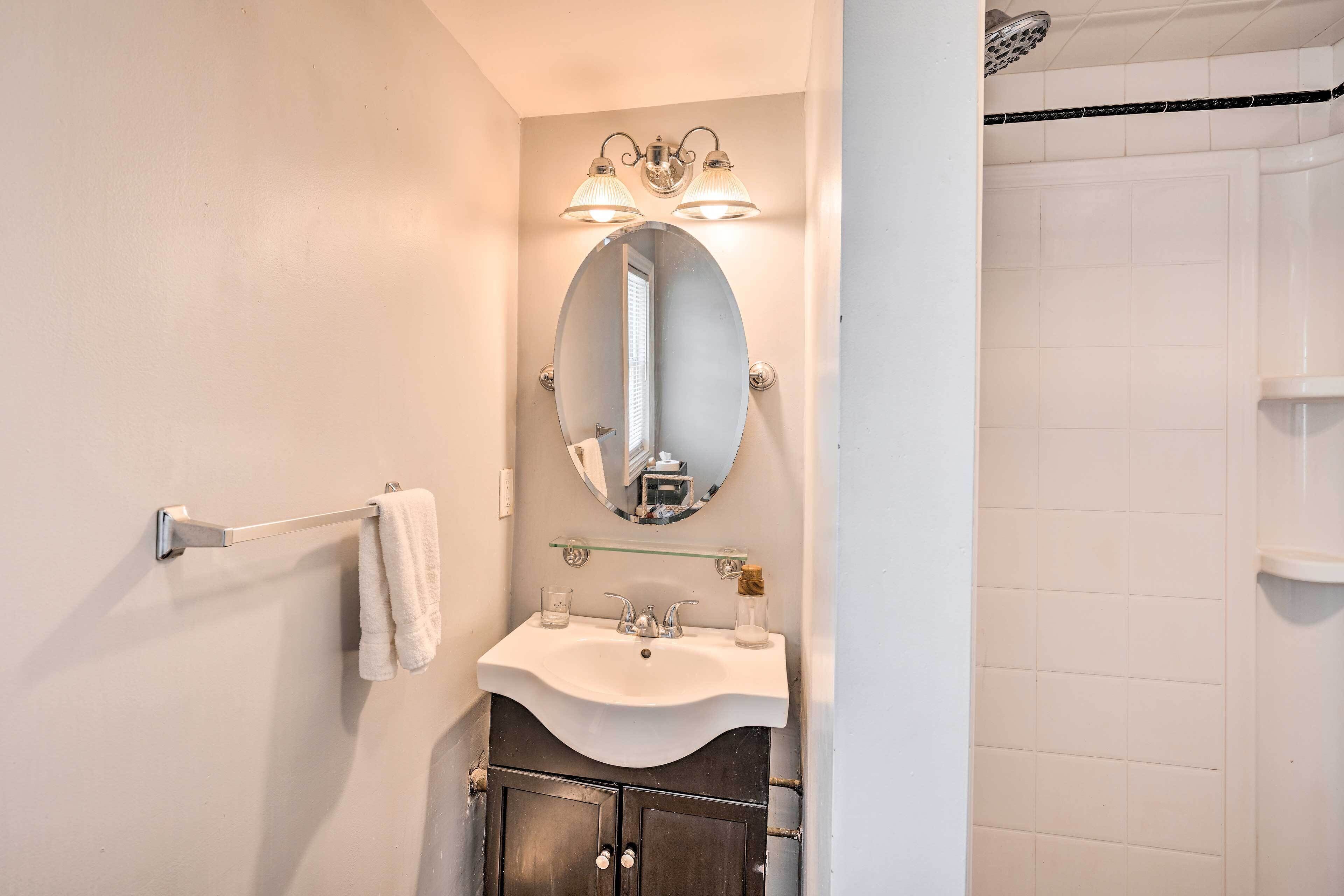 Un baño con lavamanos blanco, un espejo y un perchero para toallas.