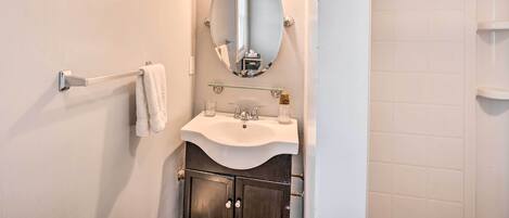 Un baño con lavamanos blanco, un espejo y un perchero para toallas.