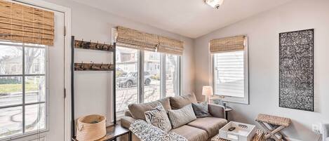 A cozy living room with a sofa, a cat tree, and a window with blinds.