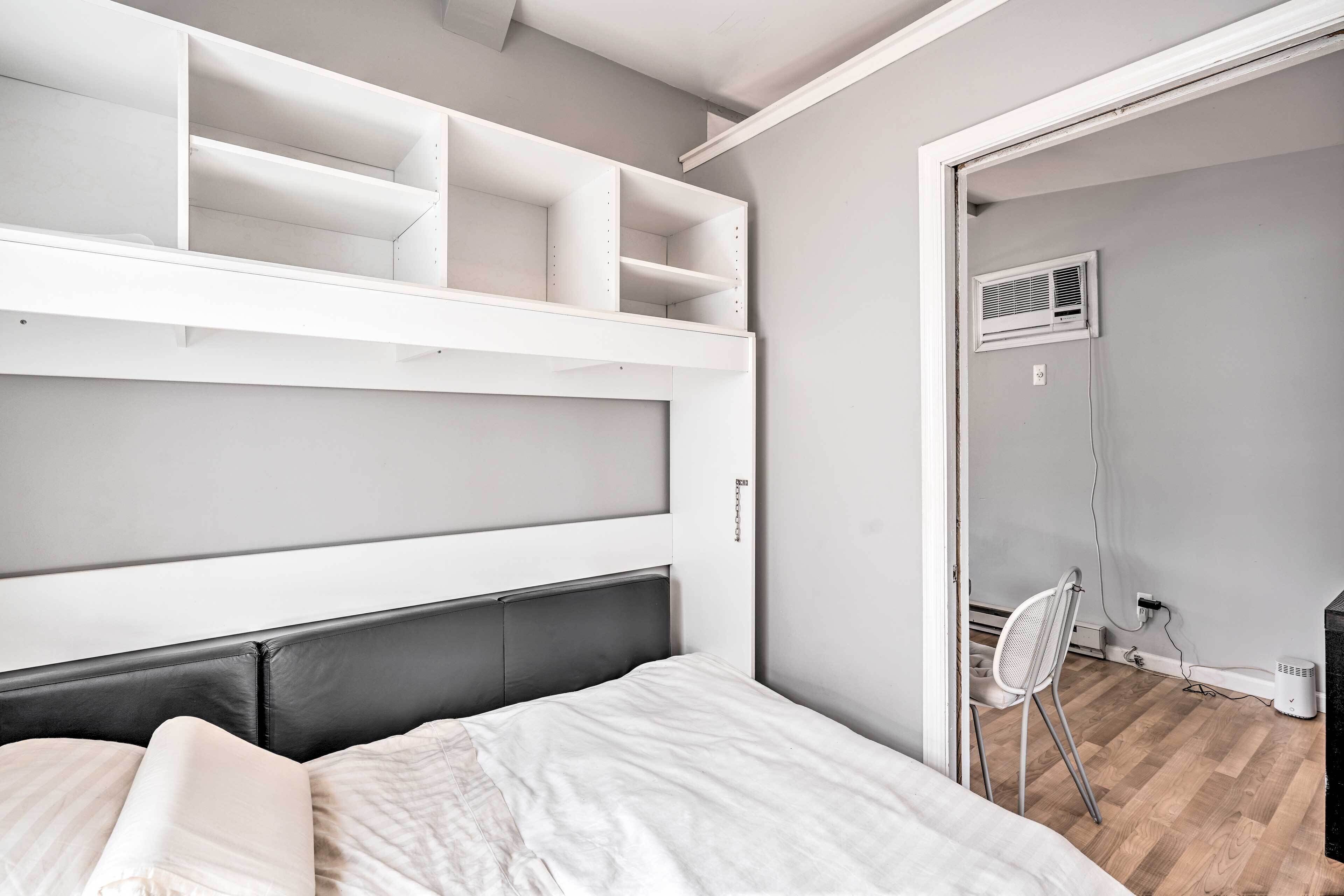 A bedroom with a bed, white headboard, and built-in shelves.
