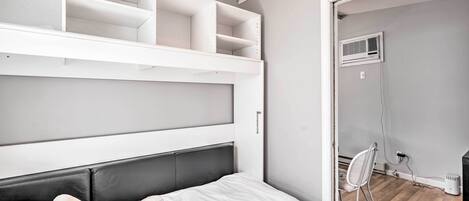 A bedroom with a bed, white headboard, and built-in shelves.