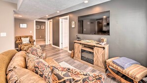 A living room with a sofa, a bench, a fireplace, and a television mounted on the wall. - Short Drive to State Parks: Herber City Apt (Heber City)