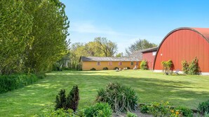 A yellow building with a red barn, surrounded by a well-maintained lawn and garden. - Pet friendly apartment in Strynø (Strynø)