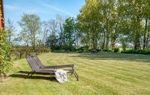 Un espacio al aire libre con césped, una silla de descanso y una manta.