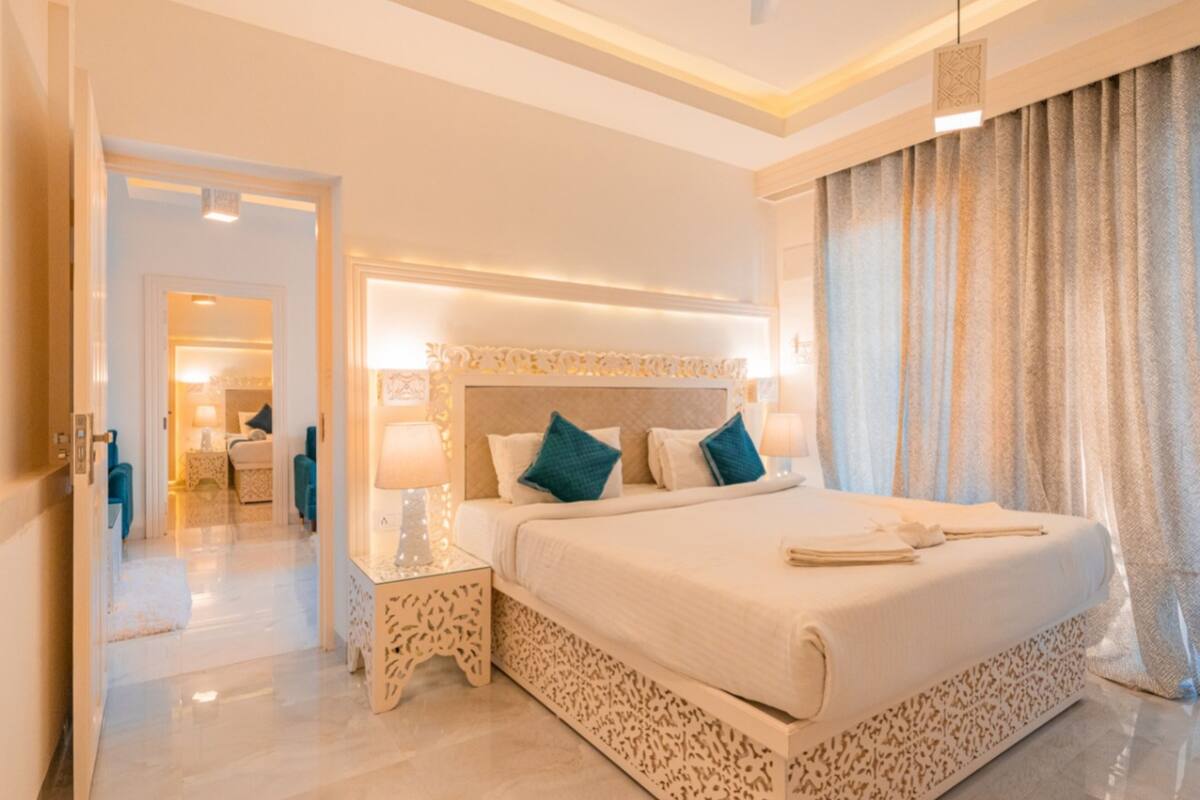 A spacious bedroom with a large bed, a nightstand, and a modern headboard.
