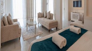 A modern hotel room with a large bed, two sofas, a small table, and a TV. - Lillywoods Zac Beach Resort (Calangute)
