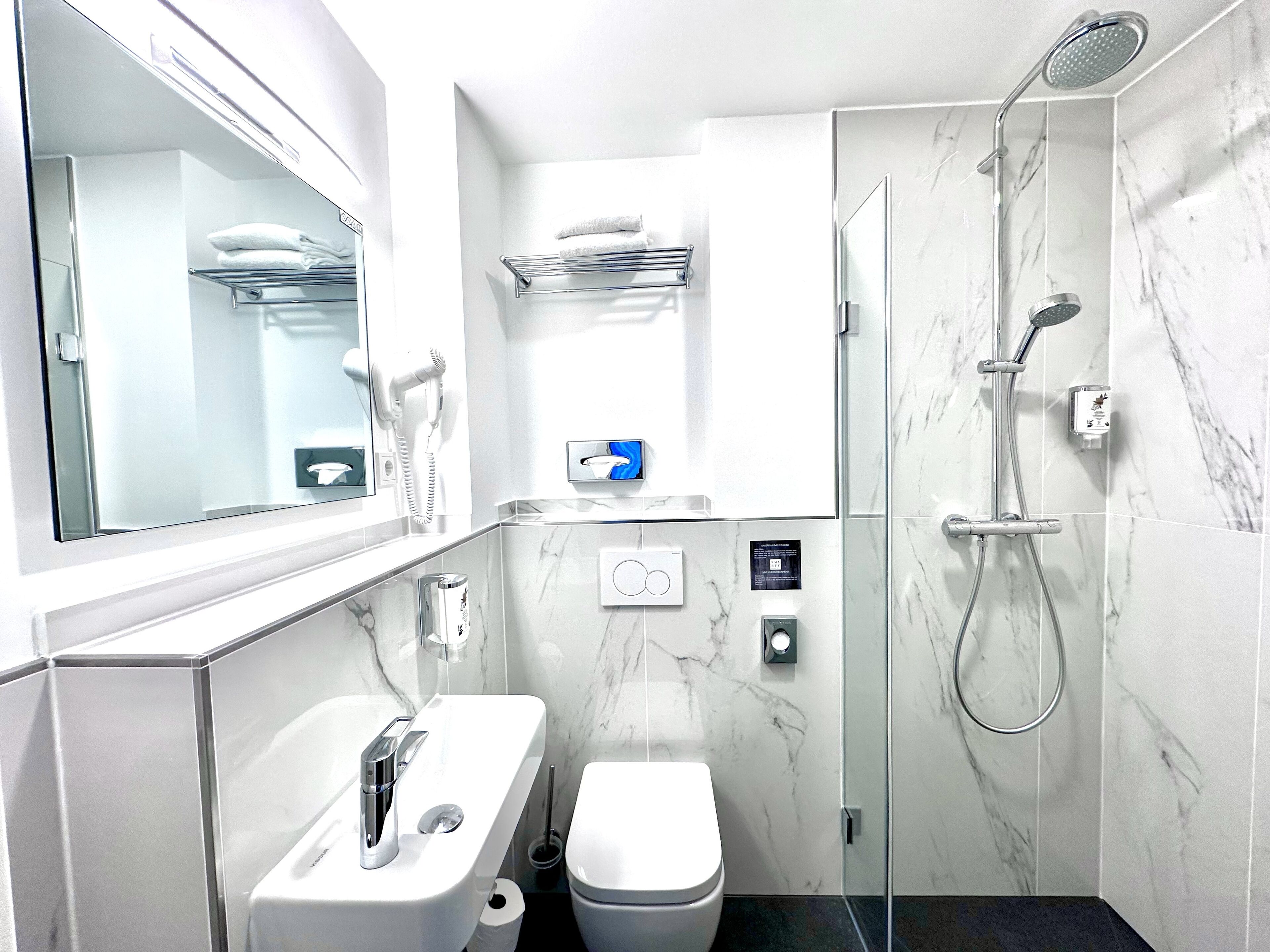 Ein modernes Badezimmer mit einem weißen Waschbecken, einer Toilette und einer Duschkabine.